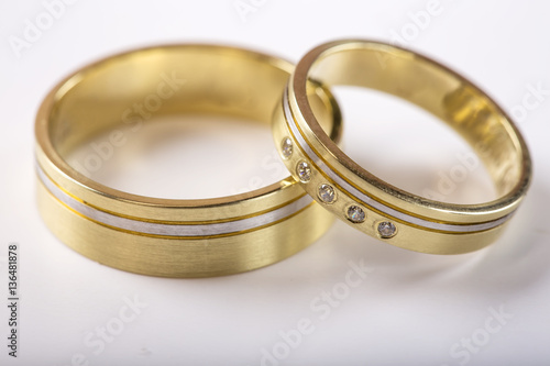 Two golden wedding rings on white with reflection