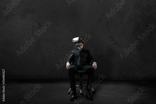 Man with Virtual Reality headset is sitting on chair on wheels i