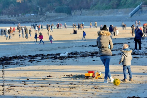Schilderij op canvas Une mère et son fils debout sur une plage de Bretagne au milieu de promeneurs