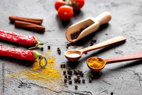 spices in wooden spoon on dark background