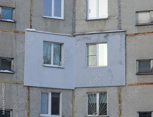 A fragment of a multi-storey concrete panel residential building with an externally applied external insulation on the facade of the apartment