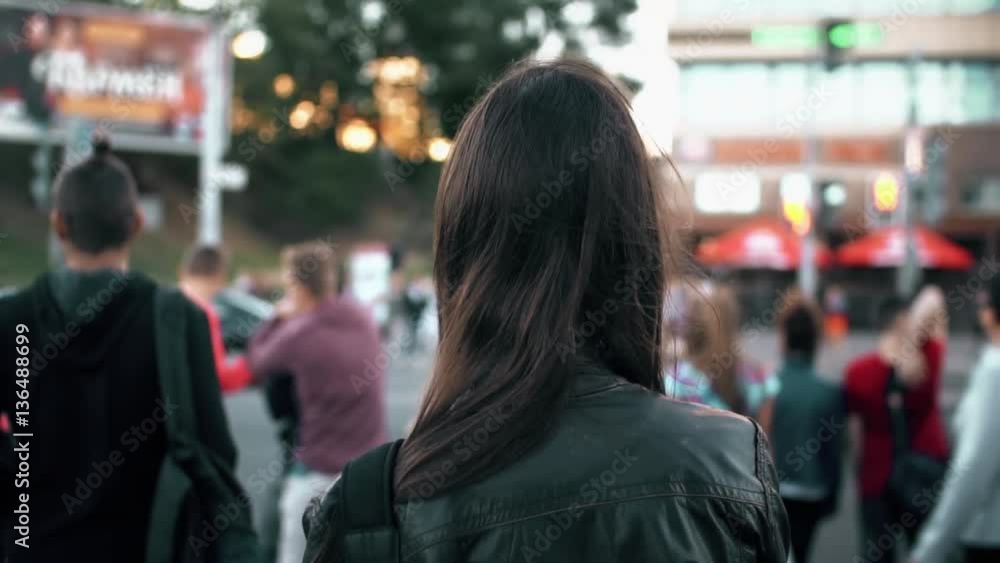 Young woman standing on street, preparing cross road at traffic lights, hair fluttering in the wind. Back view. Slow mo Young woman standing on street, preparing cross road at traffic lights, hair fluttering in the wind. Back view. Slow mo