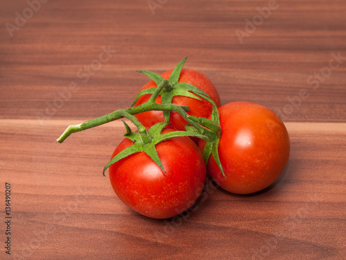 Three tomatos on wooden table photo