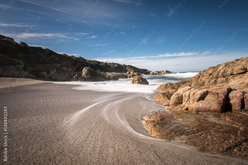 Naklejka premium Waves wash onto a small sandy cove near Calvi in Corsica