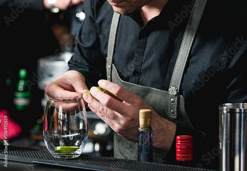 bartender making refreshing coctail with cucumber isolated on a bar background