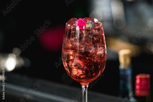 relaxing alcoholic pink coctail with a rose on top isolated on a bar background photo