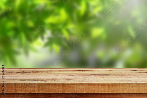 Wooden table and blur green forest background.