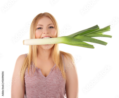 Young woman holding leek in mouth on white background