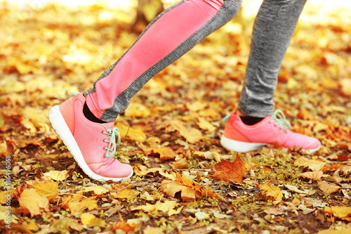 Legs of woman running in autumn park, close up view