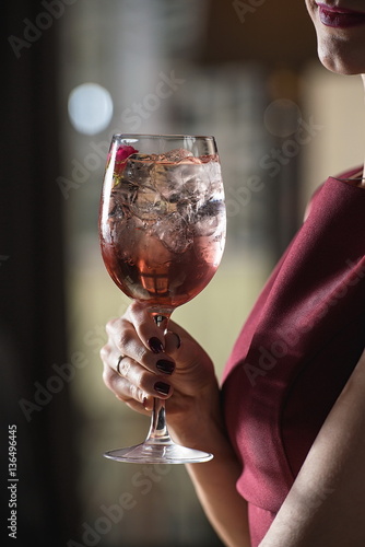 woman holds relaxing alcoholic pink coctail with a rose on top photo