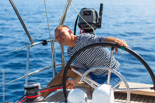 Man manages a sailing yacht during a race at sea. © De Visu