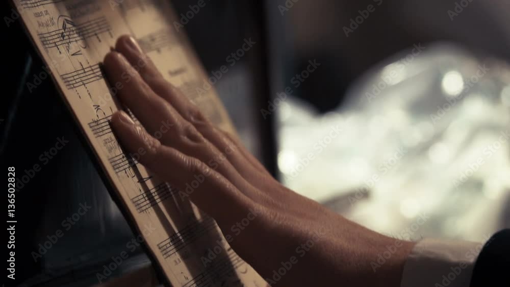 Pianist's hand holding the notes, that stand on the piano music stand Pianist's hand holding the notes, that stand on the piano music stand