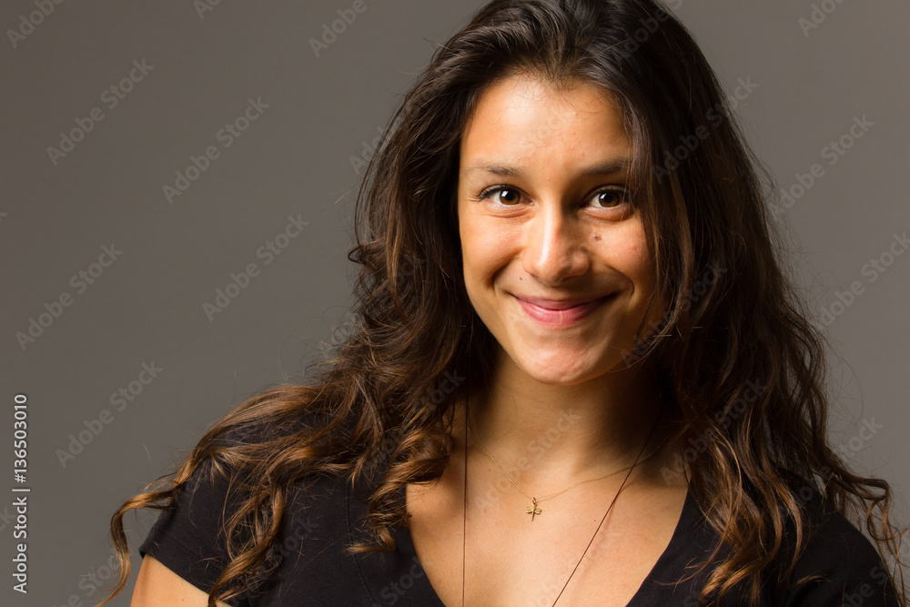 Fototapeta premium Young mixed race woman wearing a black t shirt and jeans stands in full face view while smiling at viewer
