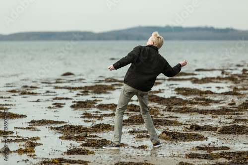 Blond boy on beach throwing a rock