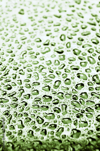 Fresh greenish drops of water on a glass surface. Selective focus this image