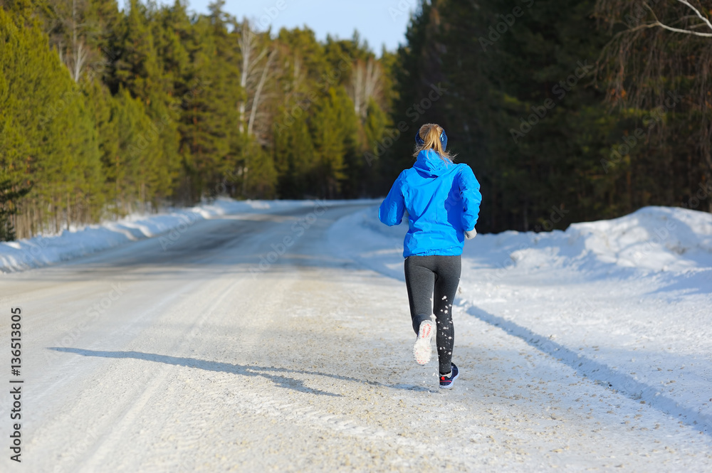 Female running sprinting up a snowy road during a winter trainin Female running sprinting up a snowy road during a winter trainin