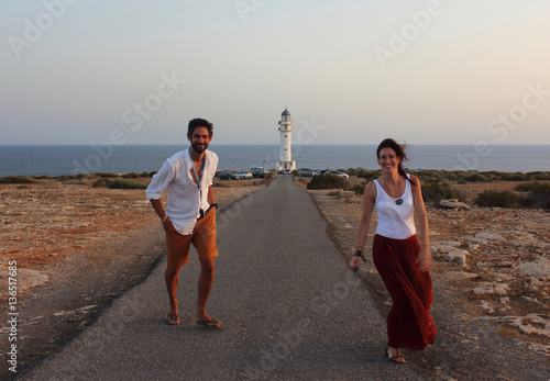 Young beautiful couple's portrait with Cap de Barberia's lighthouse on soft background, Formentera, Balearic Islands, Spain. photo