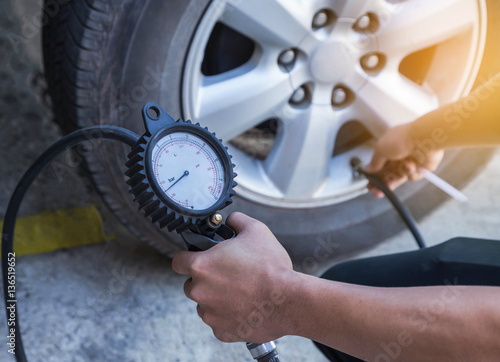 Quadro su tela Close up mechanic inflating tire and checking air pressure with gauge pressure