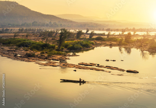 wooden fishing boat sailing in mekong river on sunrise at khongjiam district of thailand border of thailand and laos 