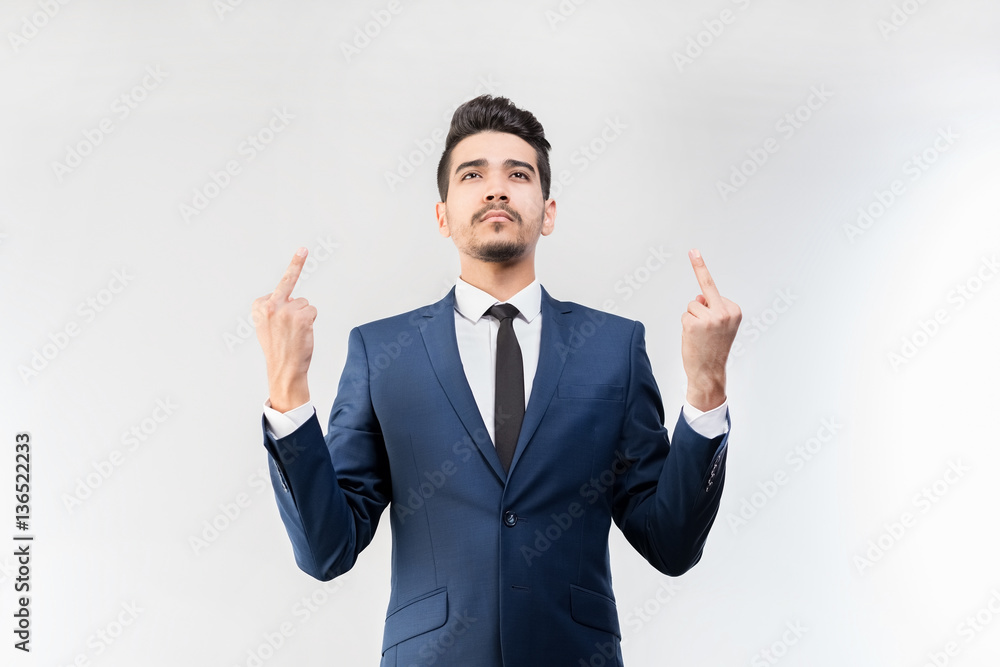 Young attractive man in a blue suit showing middle fingers on a gray background. Isolated Young attractive man in a blue suit showing middle fingers on a gray background. Isolated