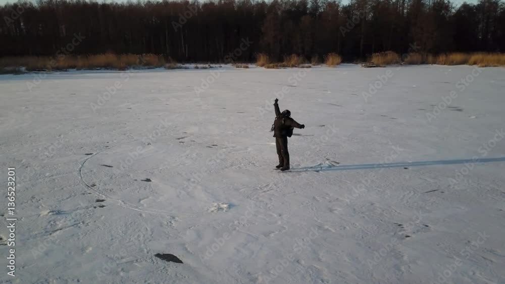 Aerial view on skater who is dancing on the frozen ice on river. Drone is rotating around the man. Aerial view on skater who is dancing on the frozen ice on river. Drone is rotating around the man.