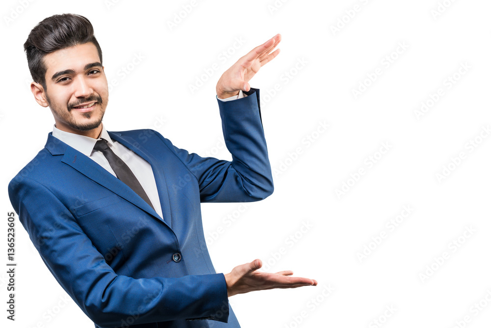 Young attractive man in a blue suit making gesture with hands on a white background. Isolated Young attractive man in a blue suit making gesture with hands on a white background. Isolated