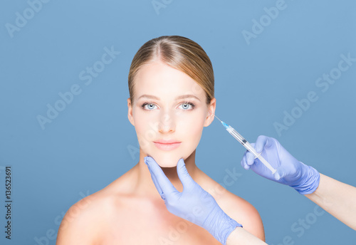 Doctor injecting botox in a beautiful face of a young woman. Pla