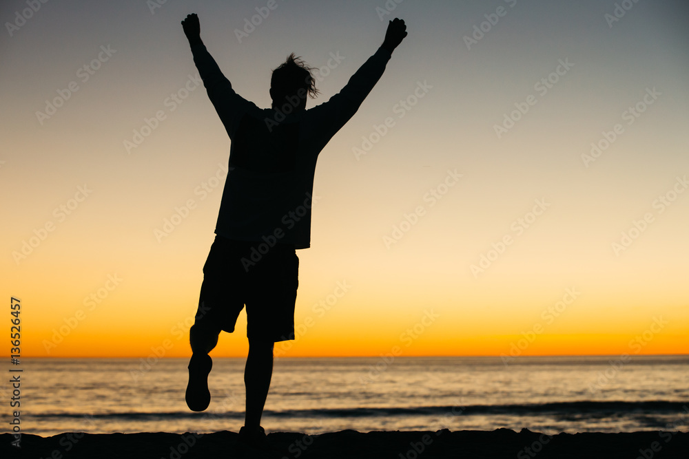 Silhouette of a happy man athlete celebrating winning success at sunset or sunrise elated with arms above his head in celebration reached his goal during hiking travel trek. Silhouette of a happy man athlete celebrating winning success at sunset or sunrise elated with arms above his head in celebration reached his goal during hiking travel trek.