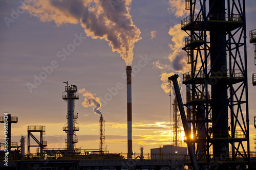 Oil Industry Refinery factory at Sunset, Petroleum, petrochemical plant, smoke comes out of  big chimneys after processing and combustion of oil