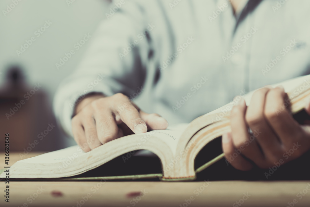 Young man is sitting on table and reading a book Young man is sitting on table and reading a book