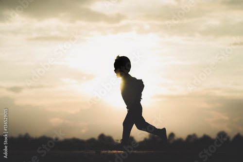 Fototapeta Naklejka Na Ścianę i Meble -  silhouette A boy run at sunset