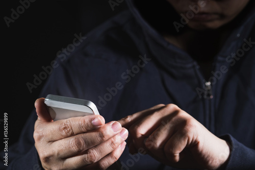 Hooded cyber crime hacker using mobile phone internet hacking in