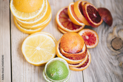 Delicious fresh fruit rainbow: orange oranges, blood oranges and green limes on the wooden table background