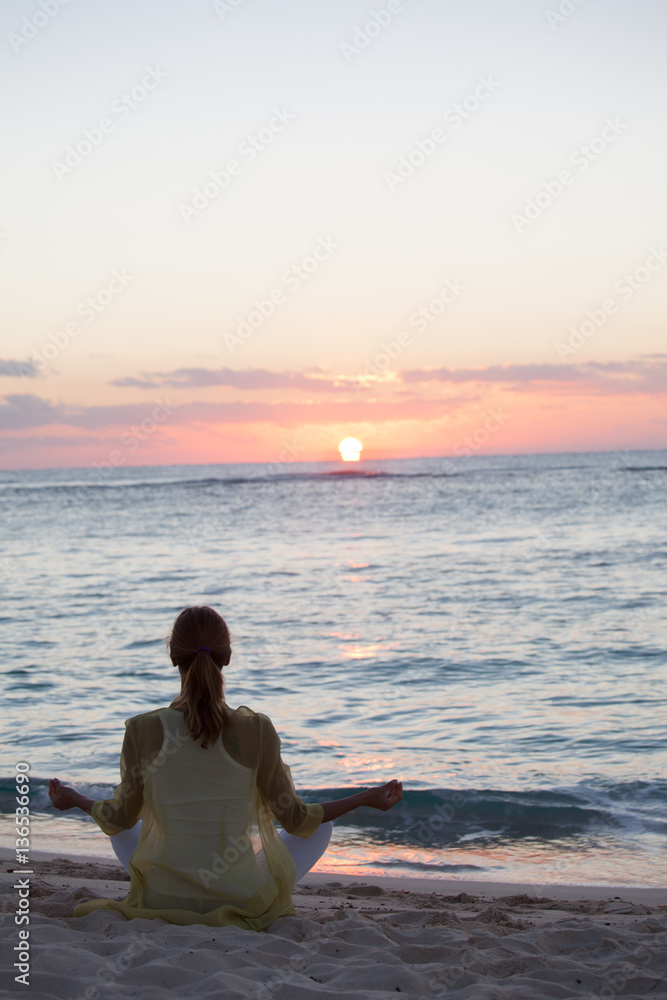 Fototapeta premium femme en position de yoga au crépuscule sur la plage