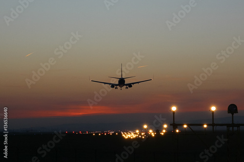 Plane lands at an airfield on the background of sunset © Bogdan