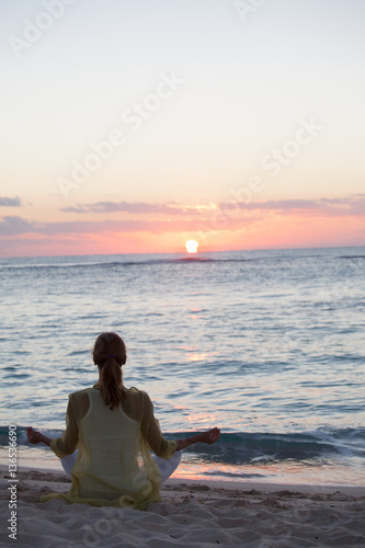 femme en position de yoga au crépuscule sur la plage
