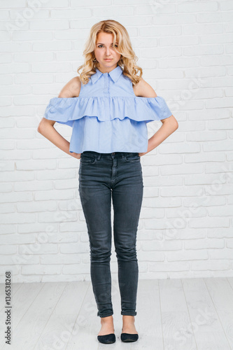 businesswoman. prepares to join the adult life. full of confidence and optimism. studio shot. White brick background. breeches, blue shirt. expensive watches. healthy skin.