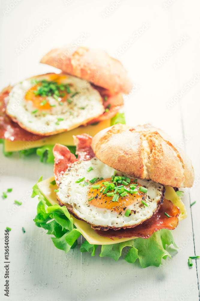 Tasty burger with bacon, eggs and cheese on white table