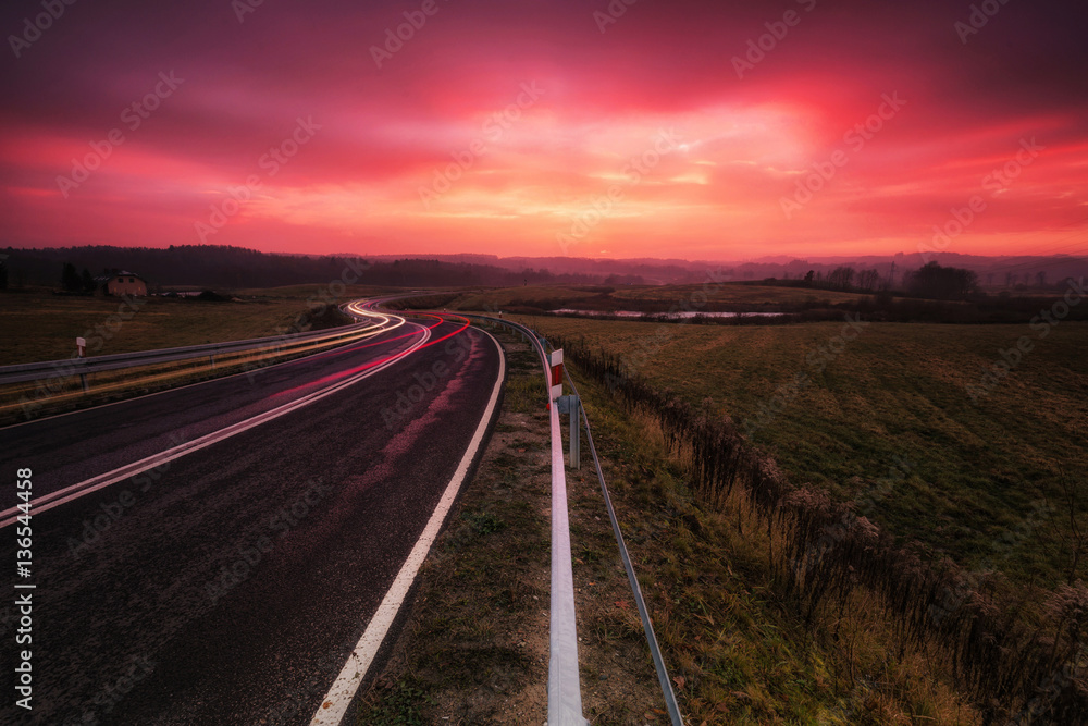 Naklejka premium Winding road during purple poppy sunset 