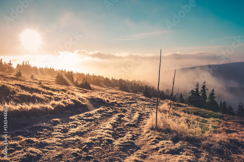 Foggy sunrise on a trail in mountains 