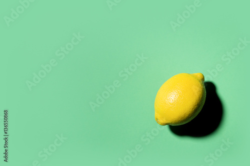 Isolated lemon projecting shadow on green background