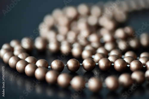 Long necklace made of brown beads on a dark background 