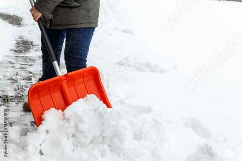 Woman with shovel cleaning snow. Winter shoveling. Removing snow after blizzard. photo