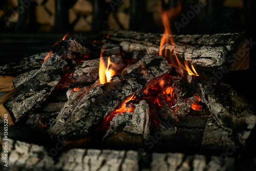 Closeup image of romantic vintage fireplace with flame from burning woods logs.Cozy sweet home concept.