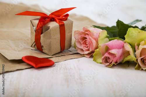 Pink roses   gift and hearts on a wooden background.