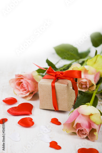 Pink roses   gift and hearts on a wooden background.