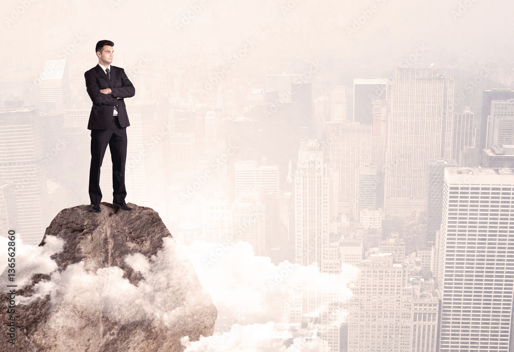 Happy businessman standing on stone top Happy businessman standing on stone top
