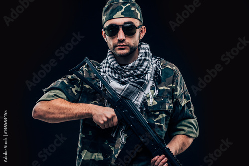 Portrait of a heavily armed masked soldier with black background concept photo