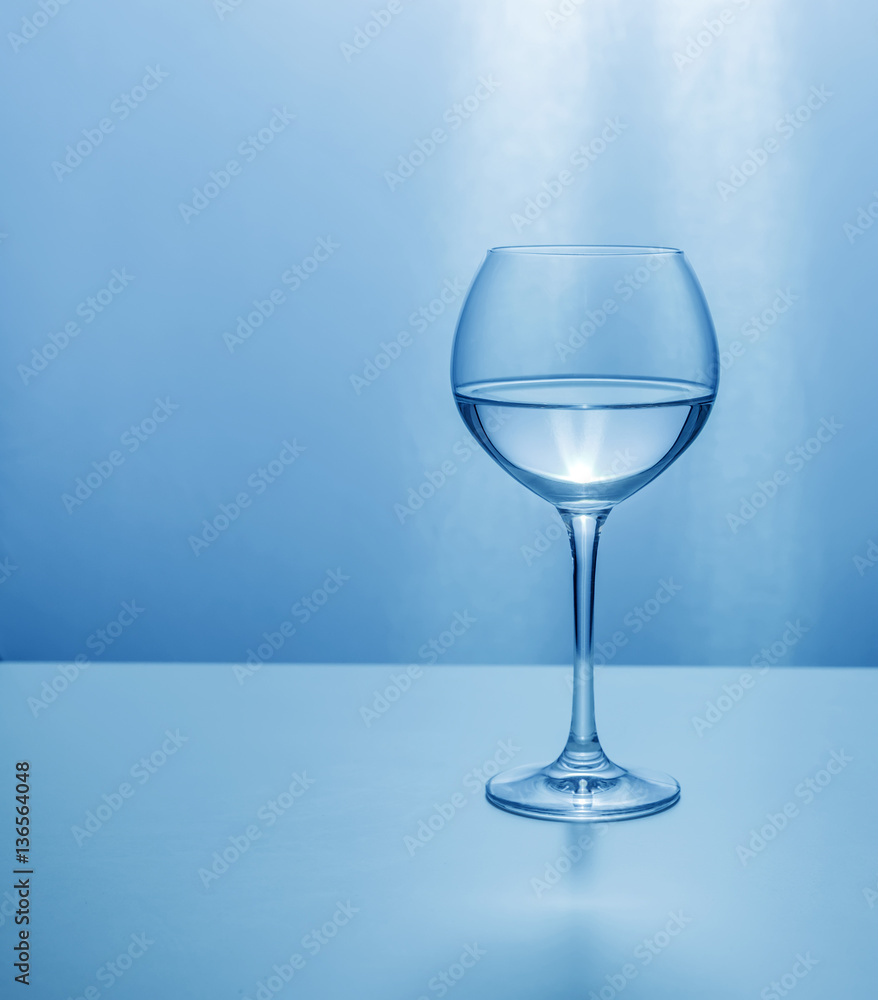Glass transparent glass half-filled with liquid in blue colors