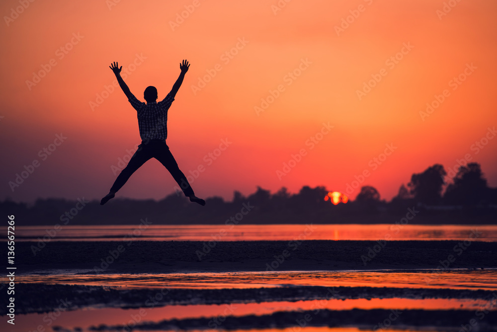 silhouette of man jumping on the beach near river.
